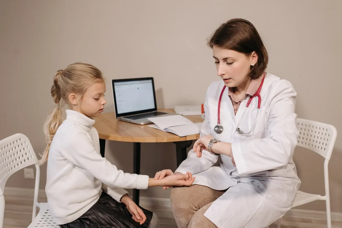 Pediatric clinician examining a young child in a consultation room