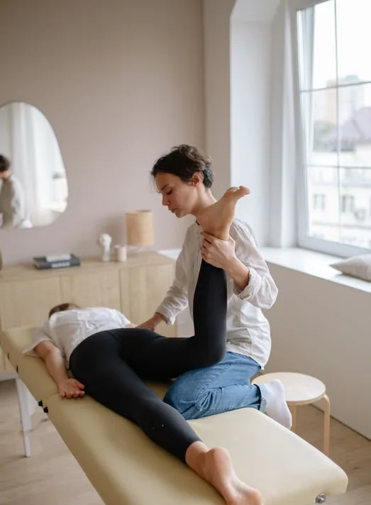 Physical therapist assisting a patient with a leg rehabilitation exercise