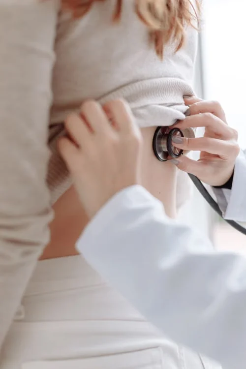 Close view of a clinician using a stethoscope on a patient’s back