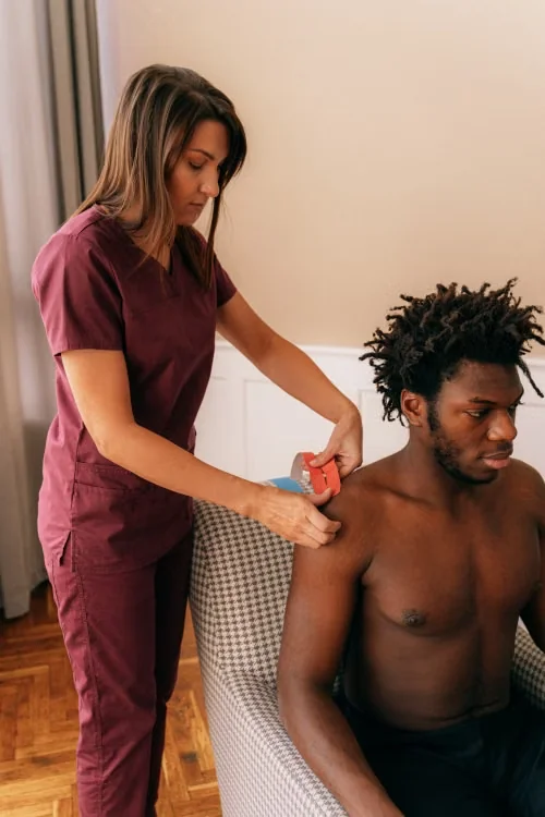 Physical therapist applying kinesiology tape to a patient’s shoulder